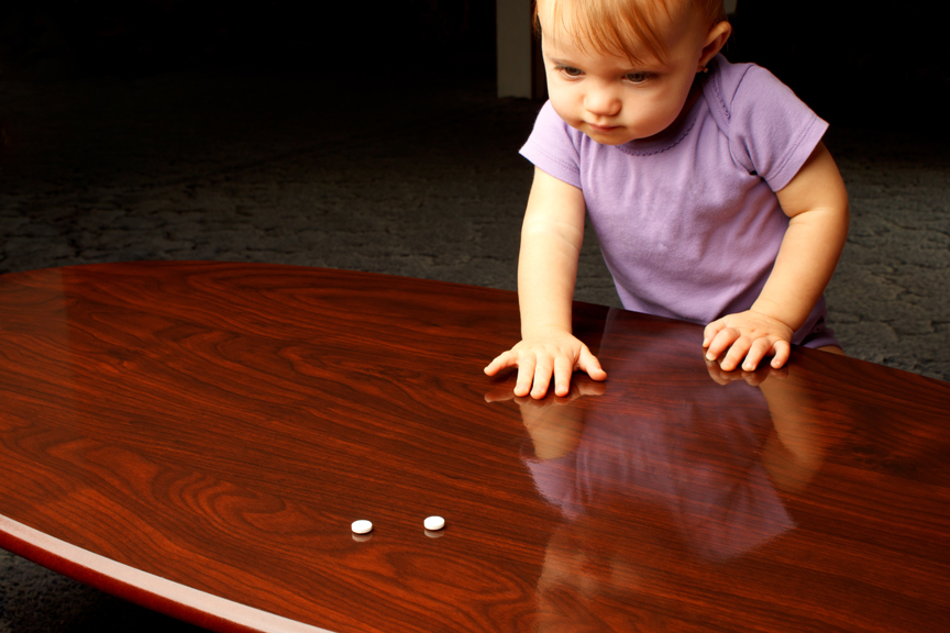 Young girl reaching for pills left on table