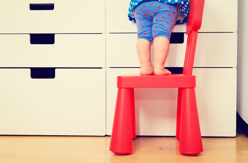 Young child standing on chair to get to countertop