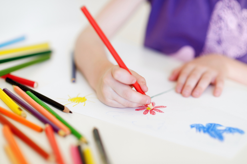 Child drawing flowers with colored pencils