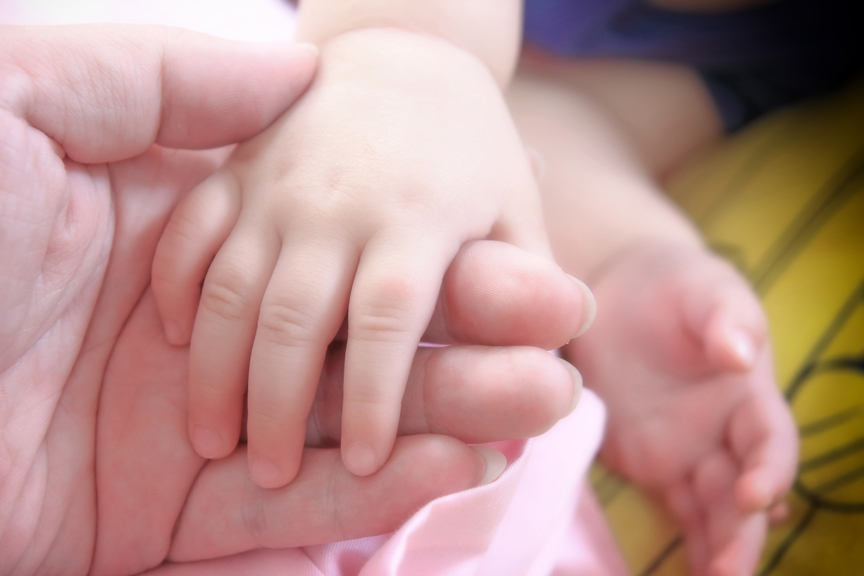 Adult hand holding small child's hand