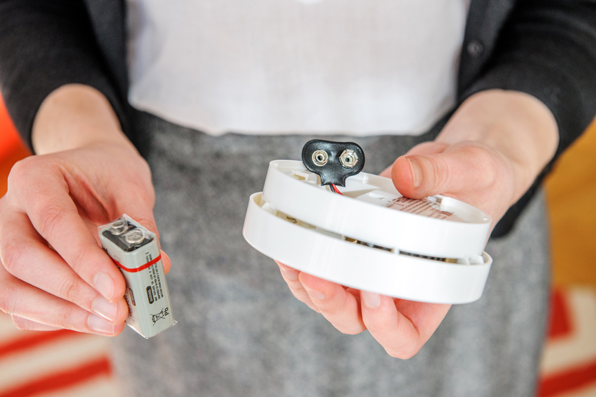 Person holding smoke alarm and battery